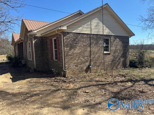 view of property exterior with brick siding and metal roof