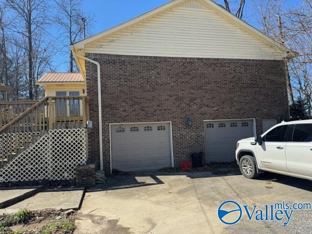 view of property exterior with a garage, concrete driveway, and brick siding