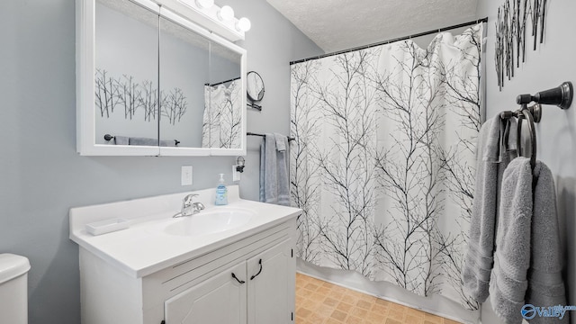 bathroom featuring curtained shower, vanity, a textured ceiling, and toilet