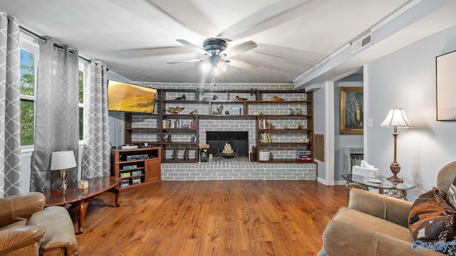 living room with baseboards, ceiling fan, visible vents, wood finished floors, and a fireplace