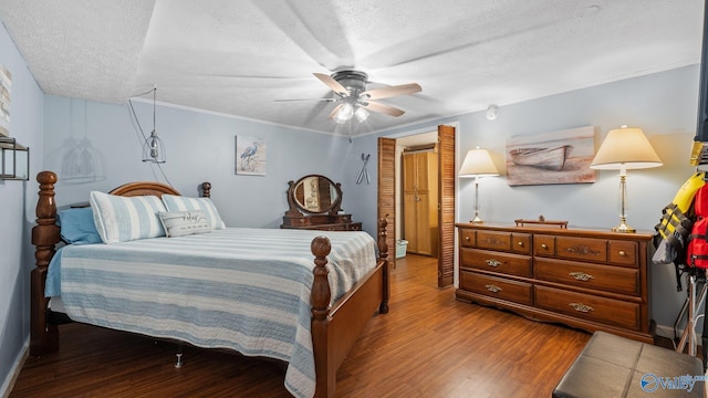 bedroom featuring ornamental molding, a textured ceiling, a ceiling fan, and wood finished floors