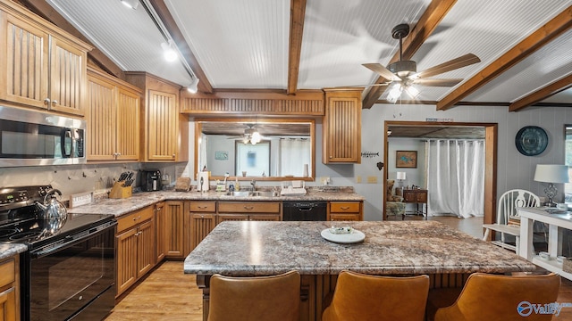 kitchen with ceiling fan, a sink, a kitchen bar, black appliances, and beam ceiling