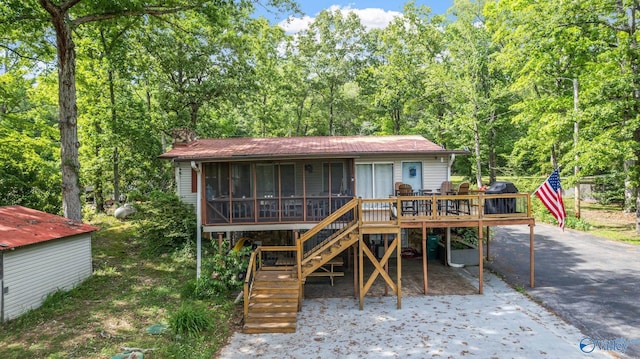 rear view of property with a sunroom, stairway, a chimney, and a deck