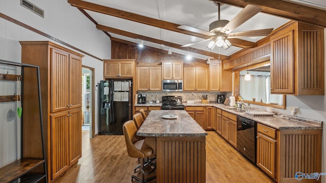 kitchen featuring a breakfast bar, black appliances, visible vents, ceiling fan, and vaulted ceiling with beams