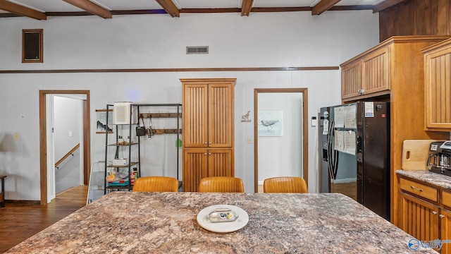 kitchen with black fridge, dark stone counters, beam ceiling, visible vents, and dark wood-type flooring