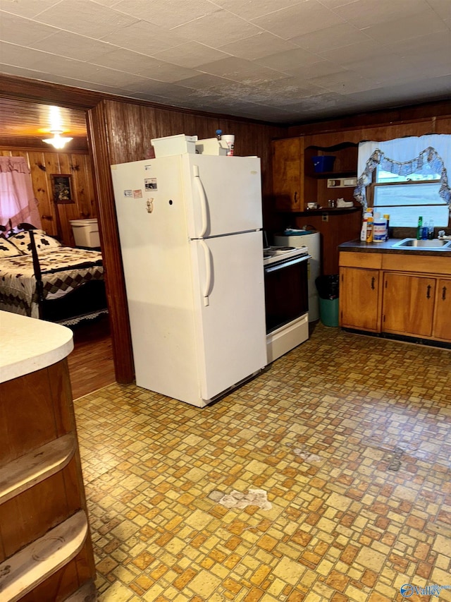 kitchen featuring a sink, white appliances, brown cabinets, and wooden walls