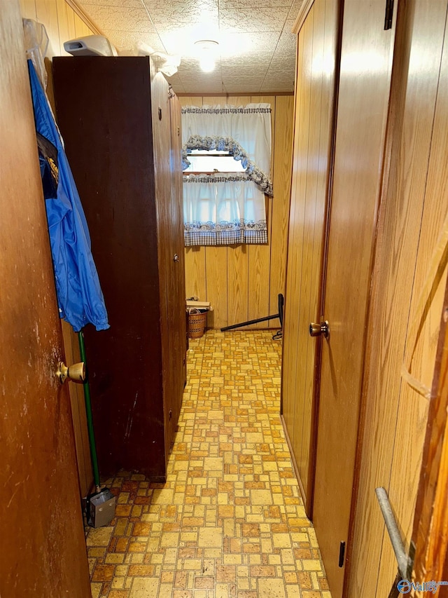 corridor featuring wooden walls and brick patterned floor