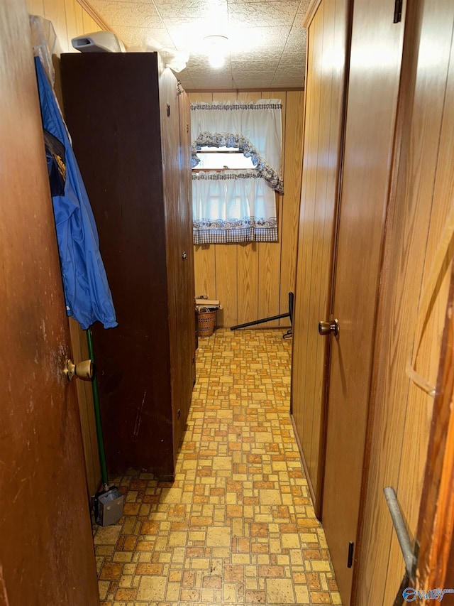 corridor featuring brick patterned floor and wooden walls