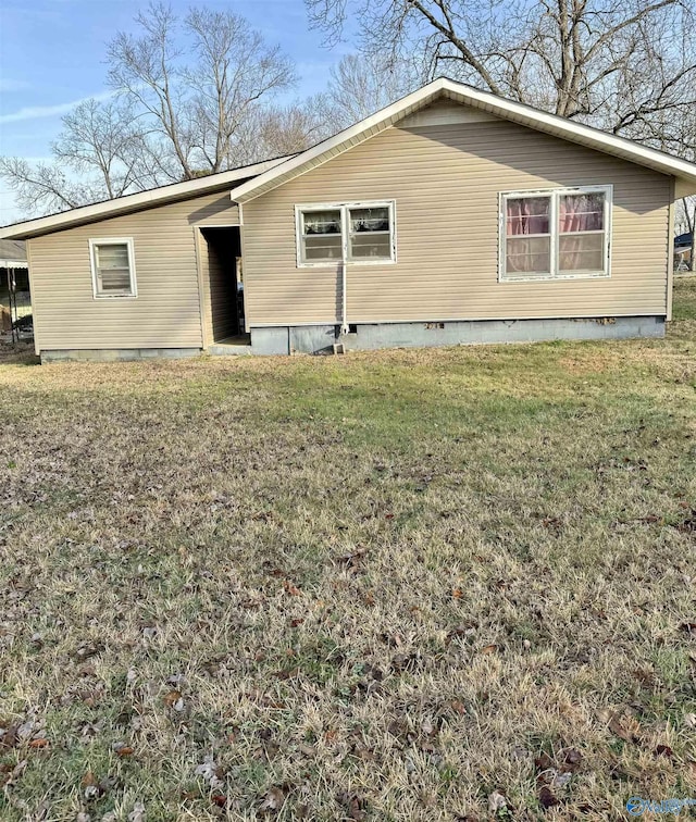 rear view of property with crawl space and a lawn