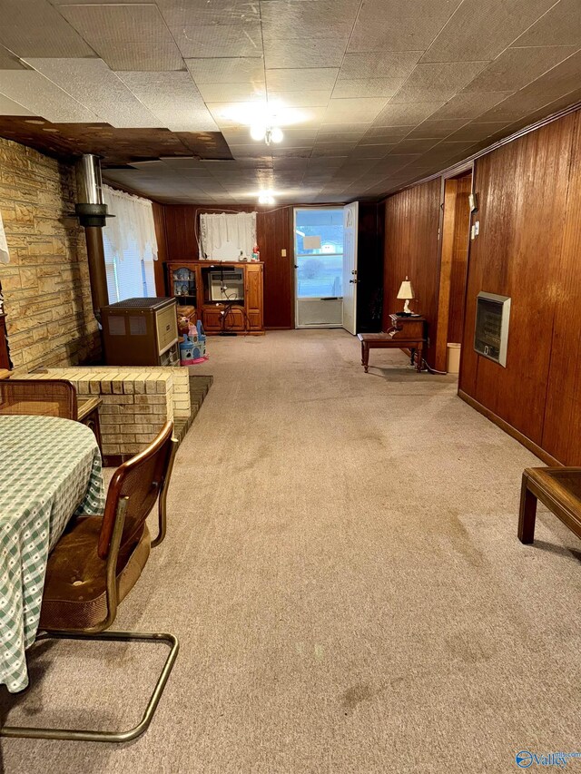 living area featuring light carpet, wood walls, and heating unit