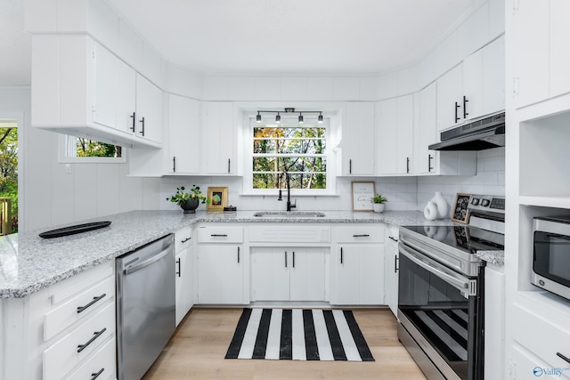 kitchen with sink, appliances with stainless steel finishes, light hardwood / wood-style floors, white cabinets, and decorative backsplash