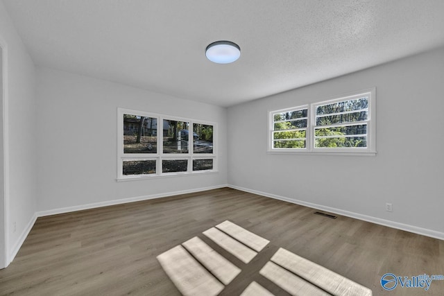 empty room with wood-type flooring and a textured ceiling