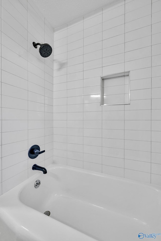 bathroom featuring tiled shower / bath and a textured ceiling