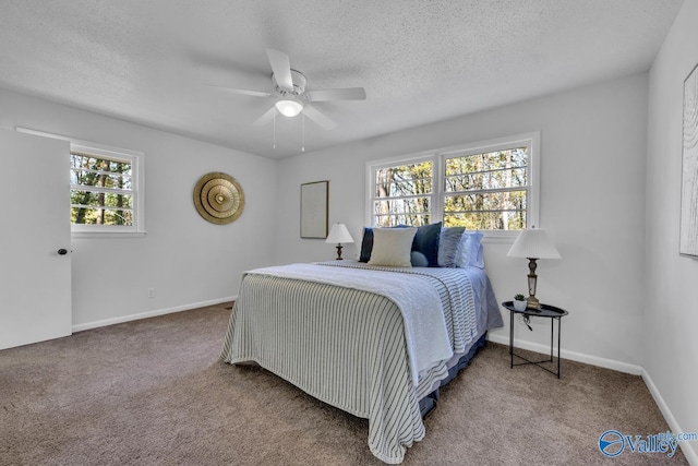 carpeted bedroom featuring ceiling fan and a textured ceiling