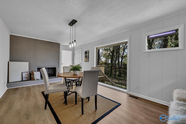 dining area with wood-type flooring, a textured ceiling, and a fireplace