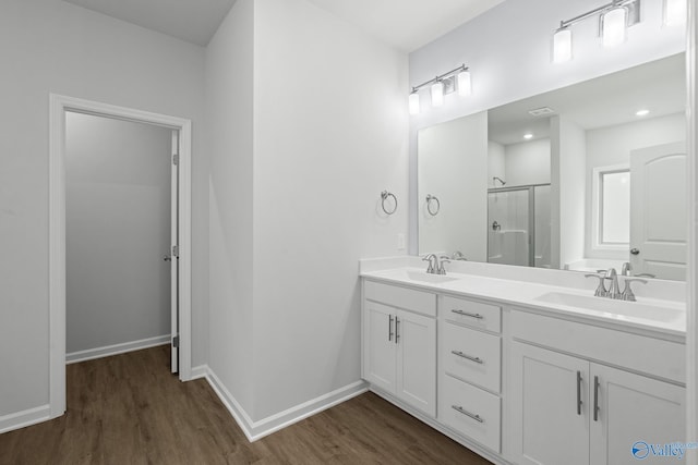 bathroom with wood finished floors, a shower stall, and a sink