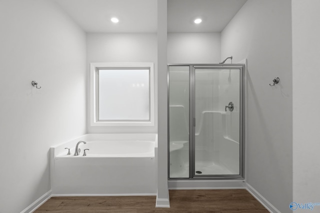 full bath featuring wood finished floors, a shower stall, a bath, and baseboards