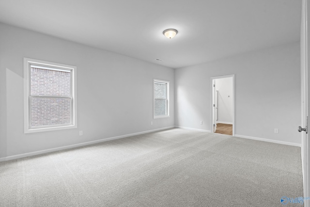 carpeted empty room featuring baseboards