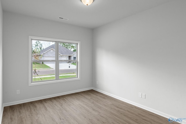 empty room featuring wood finished floors, visible vents, and baseboards