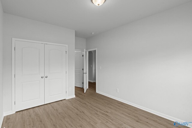 unfurnished bedroom with baseboards, wood finished floors, and a closet