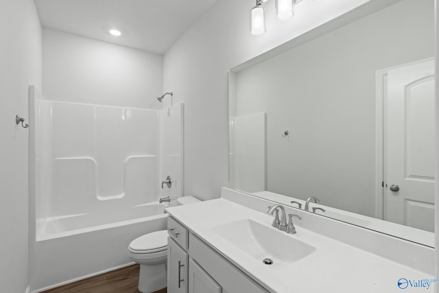 bathroom with toilet, vanity, washtub / shower combination, and wood finished floors