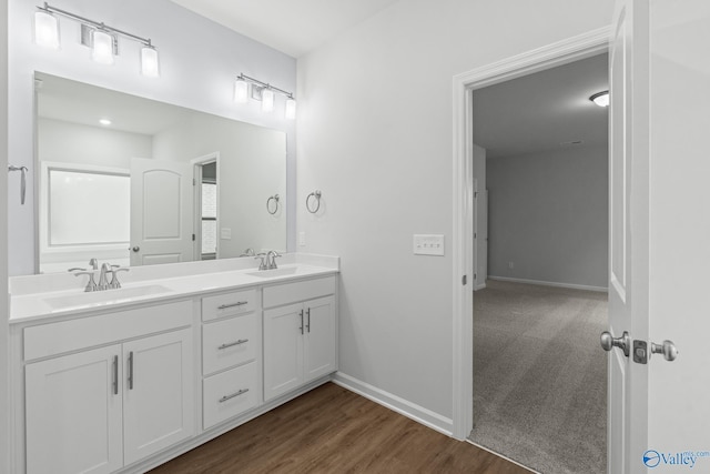 full bathroom with double vanity, wood finished floors, baseboards, and a sink