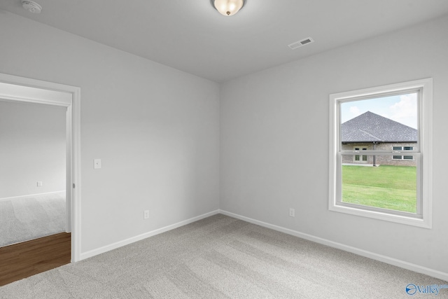 carpeted spare room featuring visible vents and baseboards