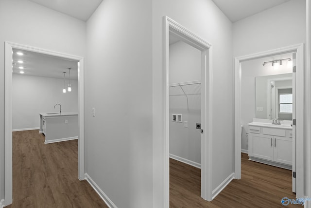 hallway with a sink, dark wood-style flooring, and baseboards