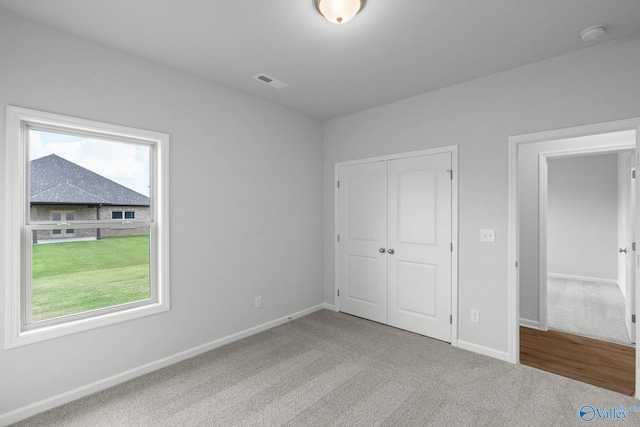 unfurnished bedroom with baseboards, visible vents, carpet floors, and a closet