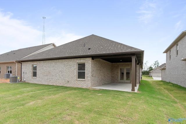 rear view of house featuring a lawn, a shingled roof, a patio area, and brick siding