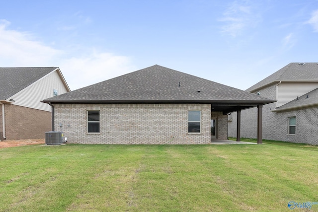 back of property featuring a yard, brick siding, a shingled roof, a patio, and central AC unit