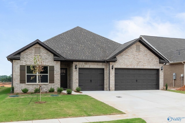 view of front facade featuring a shingled roof, a front yard, driveway, and an attached garage