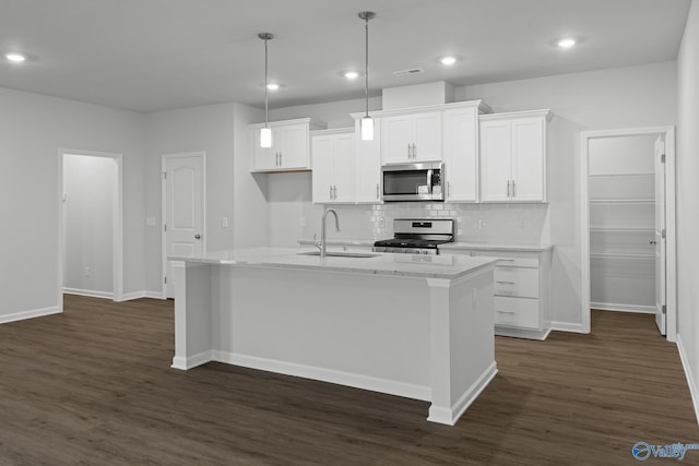 kitchen featuring white cabinets, a sink, appliances with stainless steel finishes, dark wood-type flooring, and backsplash