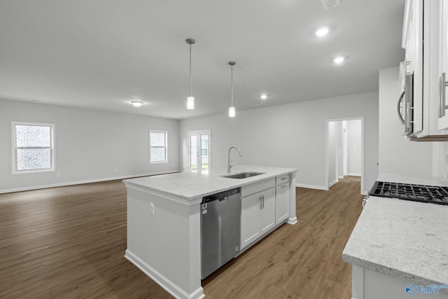 kitchen with white cabinetry, light wood-style flooring, a sink, appliances with stainless steel finishes, and a kitchen island with sink