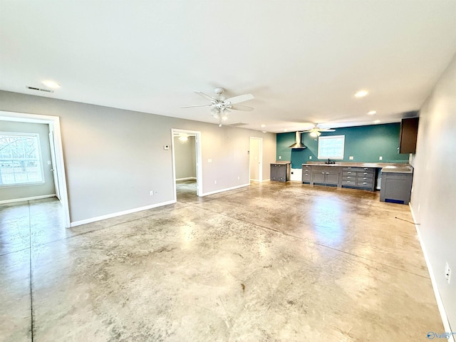 unfurnished living room featuring concrete flooring, sink, and ceiling fan