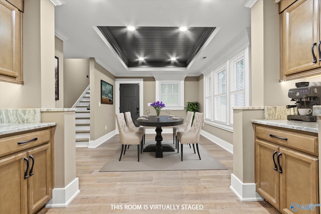 dining space with ornamental molding, light hardwood / wood-style flooring, and a tray ceiling