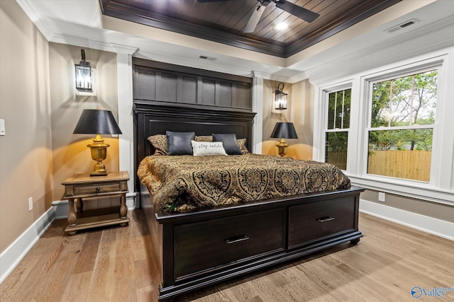 bedroom featuring crown molding, a tray ceiling, light hardwood / wood-style floors, and wooden ceiling