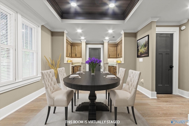 dining area with crown molding, a raised ceiling, and light wood-type flooring