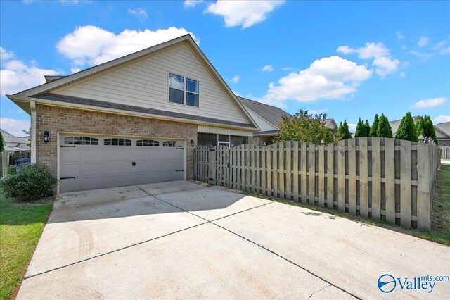 5 Leyland Dr, Huntsville, AL 35824 - view of side of property featuring a garage, brick siding, fence, and concrete driveway