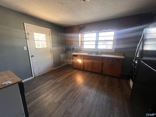 kitchen with sink, a textured ceiling, dark hardwood / wood-style floors, and black fridge