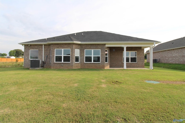 rear view of house featuring central AC unit and a lawn