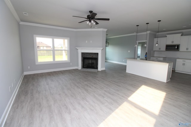 unfurnished living room featuring crown molding, ceiling fan, and light hardwood / wood-style flooring