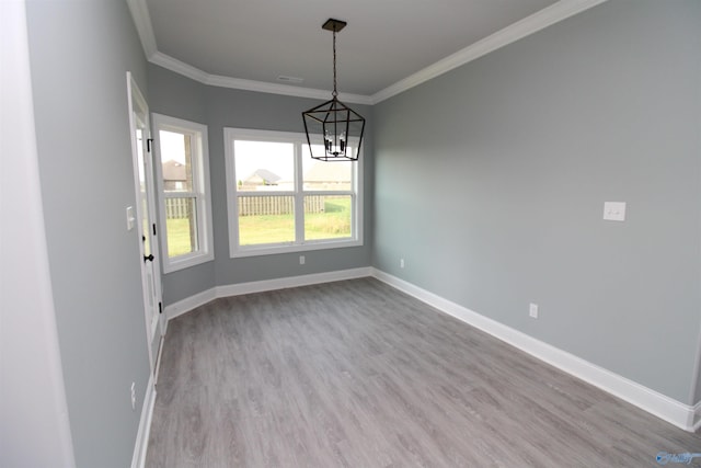 unfurnished dining area with an inviting chandelier, crown molding, and light wood-type flooring