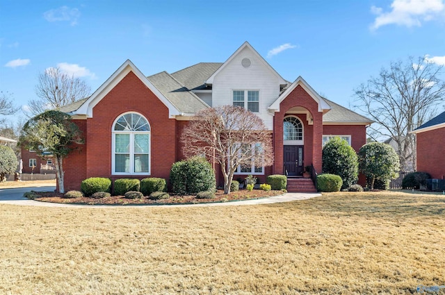 traditional-style home featuring a front yard and brick siding