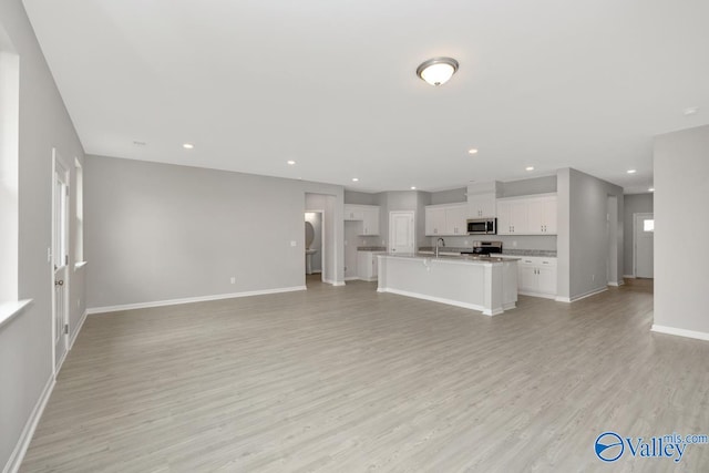 unfurnished living room with sink and light hardwood / wood-style flooring