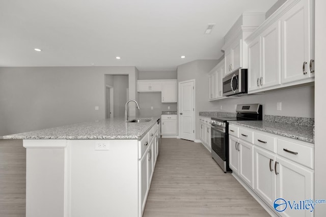 kitchen with light hardwood / wood-style flooring, white cabinets, a kitchen island with sink, and stainless steel appliances