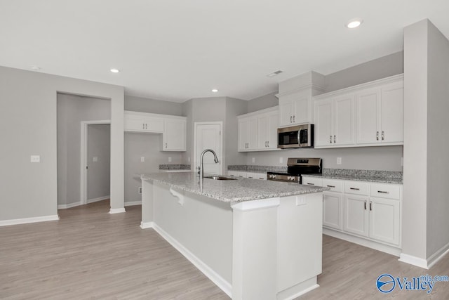 kitchen with a center island with sink, sink, white cabinetry, and stainless steel appliances