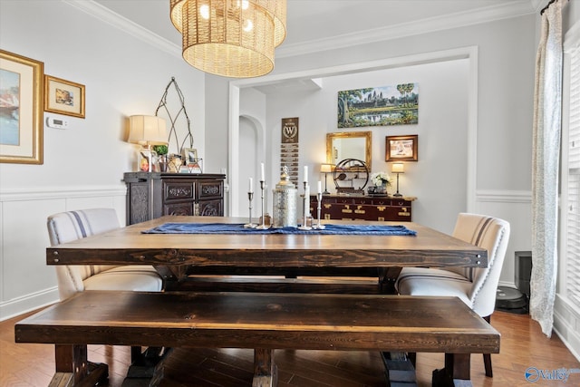 dining space featuring a notable chandelier, arched walkways, crown molding, and wood finished floors