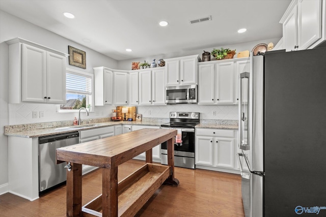 kitchen featuring stainless steel appliances, wood finished floors, visible vents, and white cabinetry