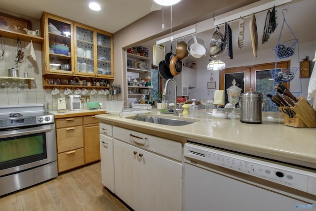 kitchen with backsplash, white dishwasher, sink, light wood-type flooring, and stainless steel electric range oven